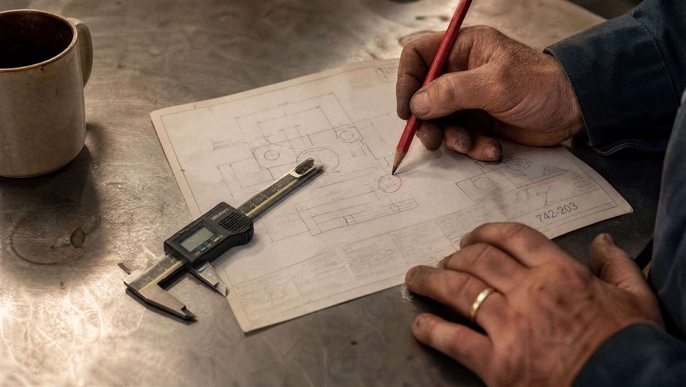 Hands marking a tolerance on an engineering drawing